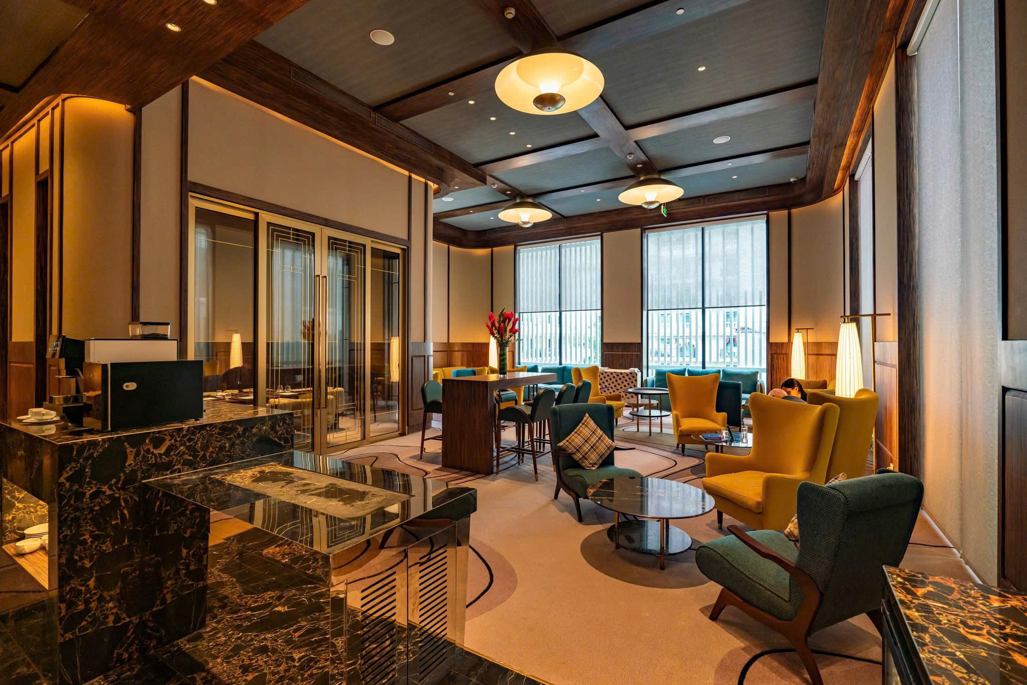 Không gian lounge khách sạn Movenpick với hệ kệ trưng bày, ghế chờ và ánh sáng ấm